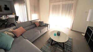 A modern living room with a grey sofa, a round coffee table, and a dining area in the background. - Beautiful Villa Zara Blu with pool (Briševo)