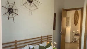 A neatly made bed with white and green pillows, a wooden headboard, and two wall decorations resembling spider webs. - SAND AND SALT, terrace 25 mts, air conditioning and direct access to the pool. (deltebre)
