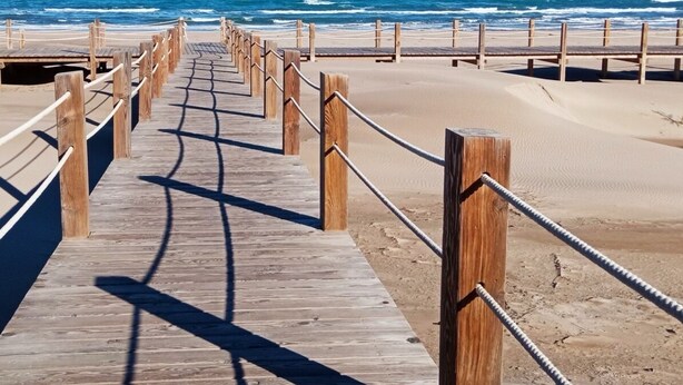 A wooden boardwalk leading to a beach with a railing on one side. - SAND AND SALT, terrace 25 mts, air conditioning and direct access to the pool. (deltebre)