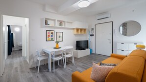 A compact living space with a dining area, a sofa, a TV, and a small kitchen area. - Lovely apartment for 4 guests with A/C, WIFI and TV (Pavia)