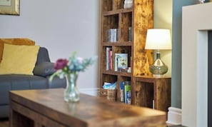 Un salon avec un canapé, une bibliothÚque en bois, une table avec un vase et une lampe.