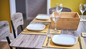 A dining table set with plates, cutlery, and glasses, with a wooden box and a chair in the background. - Vacant Nests | The Park View | Seaham Hideaway (County Durham)
