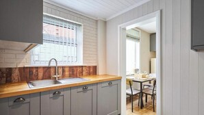 Cuina amb finestra, un rentapeus i zona de menjador amb taula i cadires.