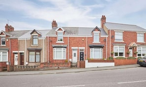 A row of red brick terraced houses with pitched roofs, front doors, and small front gardens. - Vacant Nests | The Park View | Seaham Hideaway (County Durham)