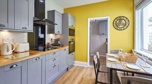 Una cocina moderna con armarios grises, encimera de madera y un comedor con mesa para dos.