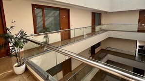 Een meerlaags atrium met glazen balustrades, plantenbakken en een dakraam.