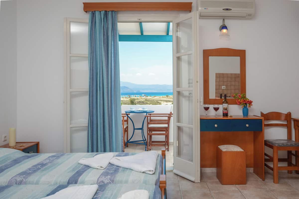 Ein Schlafzimmer mit Bett, Schreibtisch, Stuhl, Tisch und Meerblick.