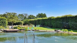 Ein ruhiger Poolbereich im Freien mit Holzterrasse, Metalltreppe und gepflegtem Heckenstreifen.