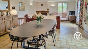 Ein geräumiger Essbereich mit einem großen runden Tisch, einer floralen Dekoration und modernen Stühlen.