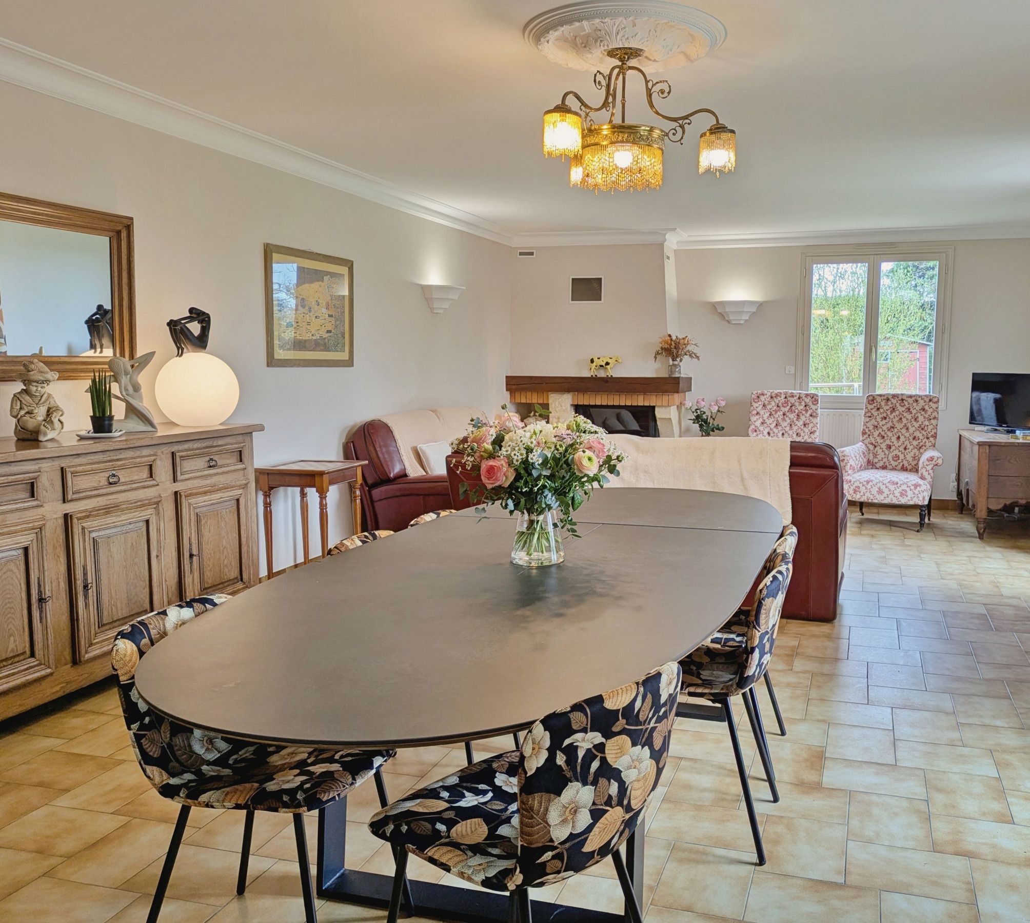 A spacious dining area with a large round table, floral centerpiece, and modern chairs.