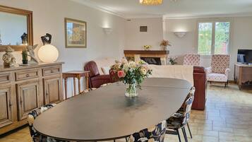 A spacious dining area with a large round table, floral centerpiece, and modern chairs.
