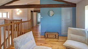A spacious room with wooden beams, a blue accent wall, and a wooden bench. - Spacious cottage for 12 with private garden and spa in Chevrières (Chevrières - Loire)