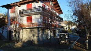 A multi-story building with balconies, a parked vehicle, and a fenced area. - Bright 3-room apartment - Pyrenees view and parking (Font-Romeu-Odeillo-Via)