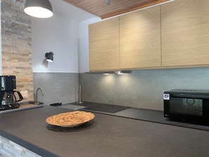 Cocina moderna con microondas incorporado, cafetera y una cesta tejida sobre la encimera.