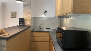 A modern kitchen with wooden cabinets, a built-in stove, and pendant lighting.