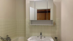 A bathroom with a white sink, a mirror above it, and a wooden cabinet below.