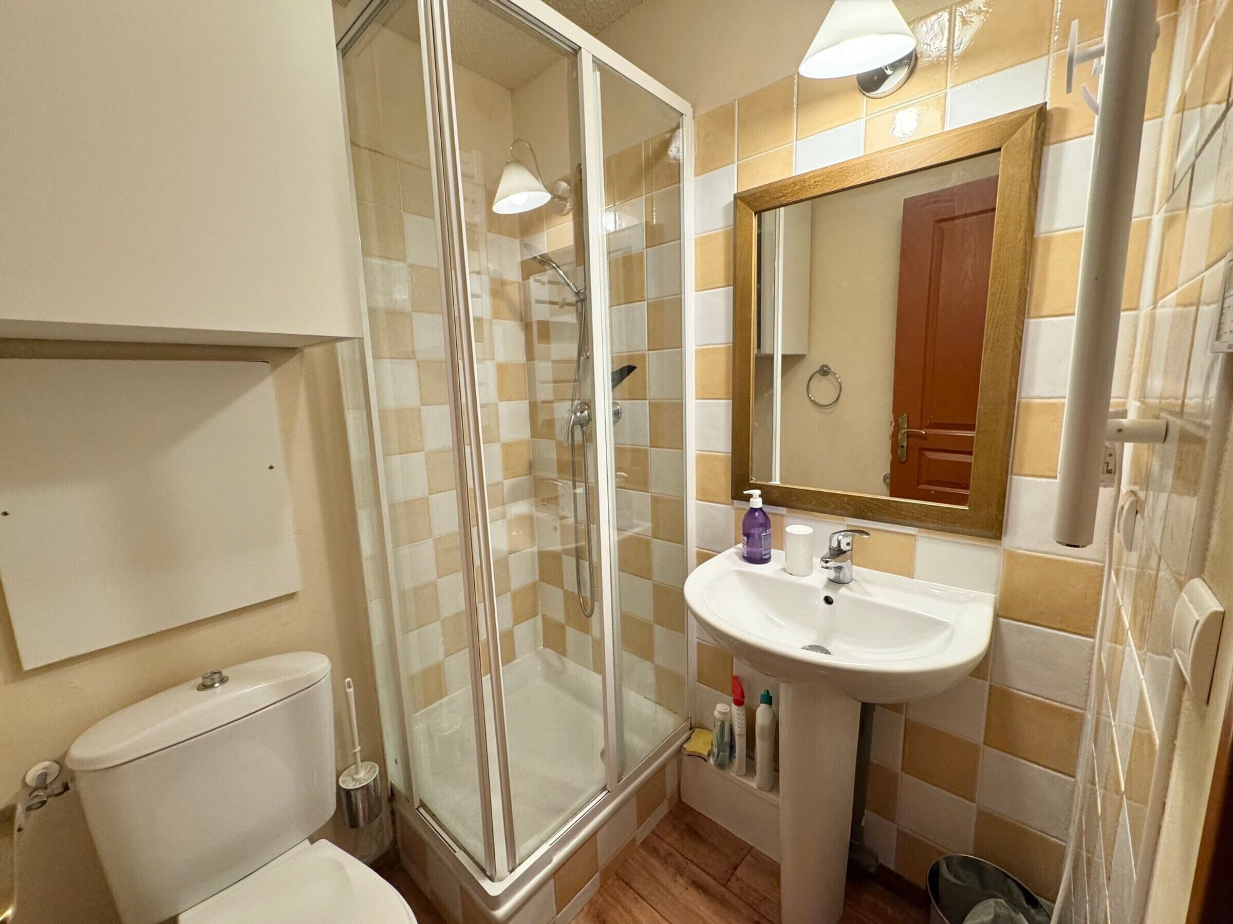 Un baño con cabina de ducha de vidrio, un lavamanos blanco y un espejo encima.