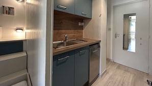 A modern kitchen with dark cabinets, a wooden countertop, and a built-in dishwasher.