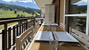 A dining table set for two on a balcony with a scenic mountain view.