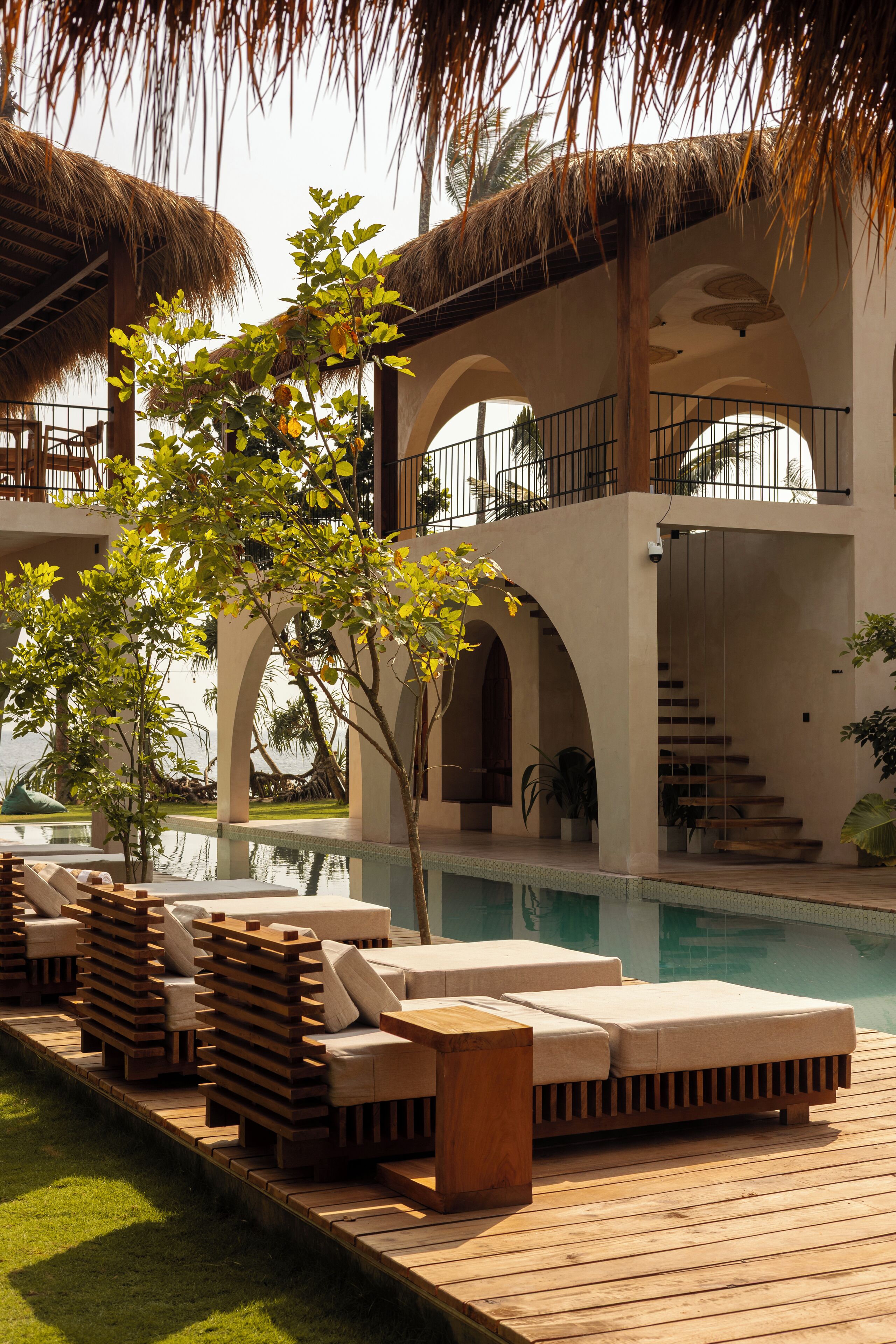 A poolside area with lounge chairs and a staircase leading to an upper level.