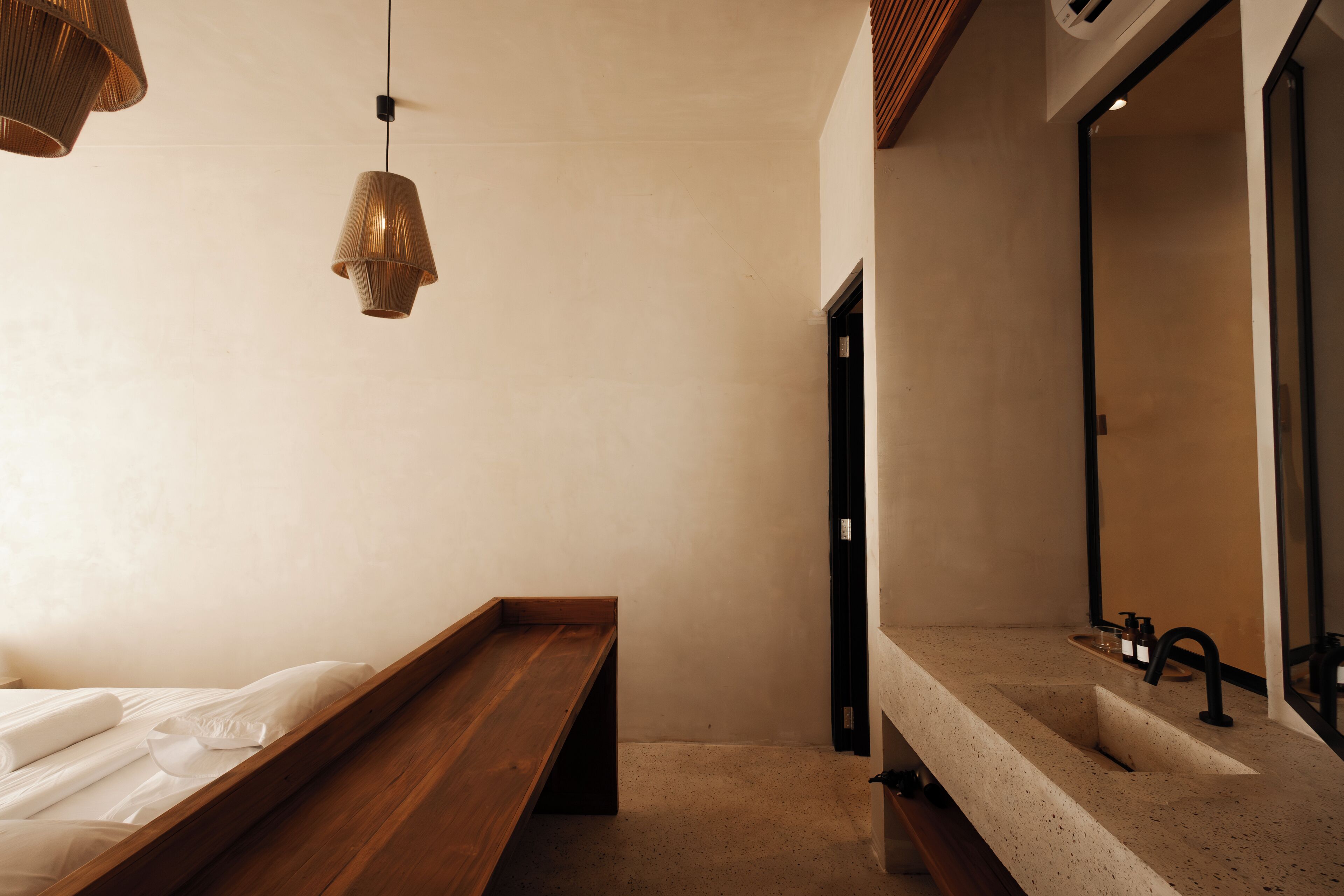 Un baño minimalista con un banco de madera, un espejo grande y un lavamanos.