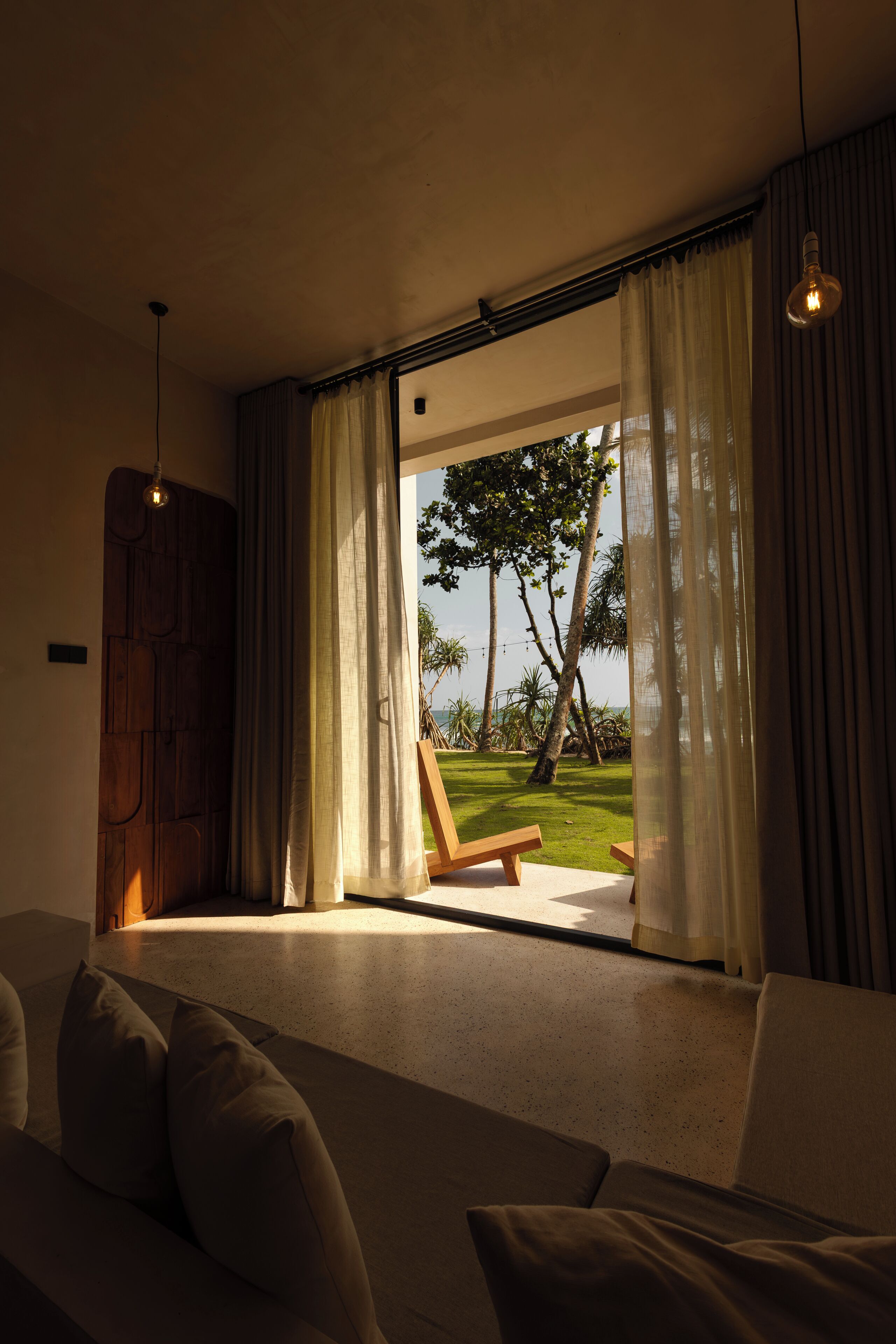 Una habitación moderna con un ventanal grande, una puerta de madera y un sofá.