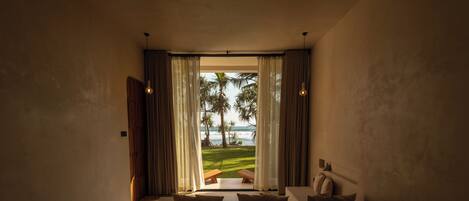 Una camera da letto con un letto grande, vista sull'oceano e un patio con tavolo e sedie.