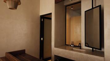 Un baño moderno con bancos de madera, un espejo grande e iluminación colgante.