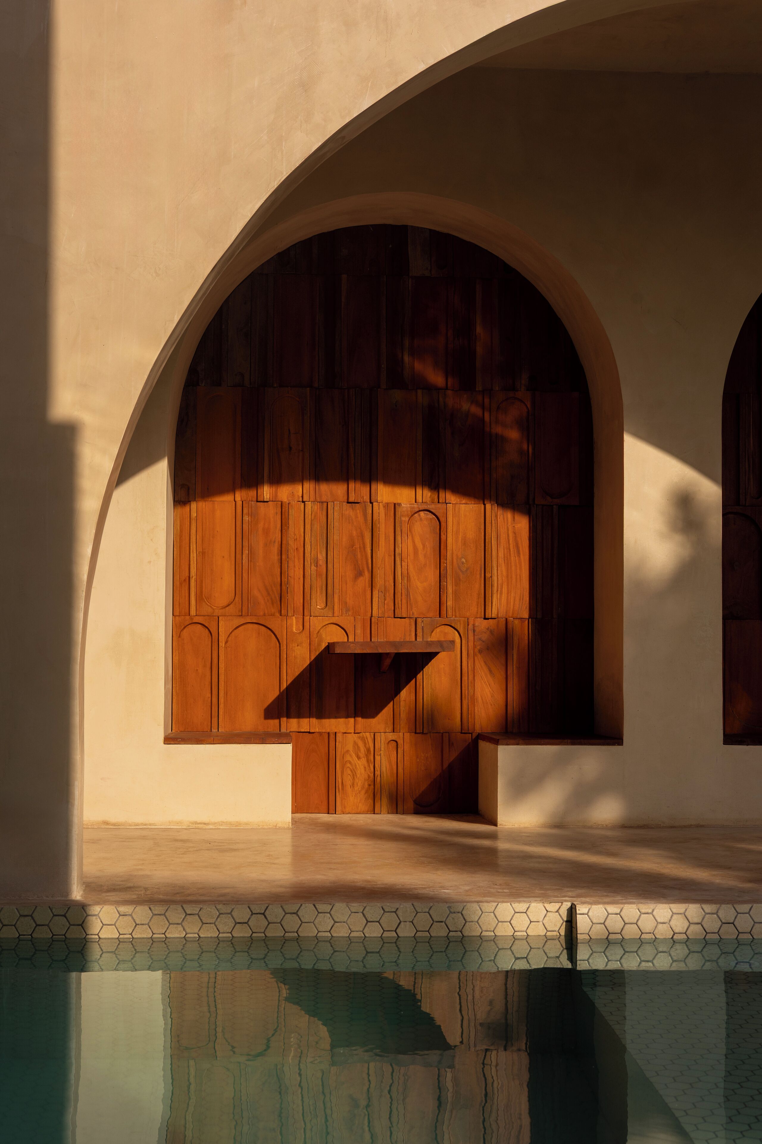 A pool with a hexagonal tile pattern and a wooden door with a geometric design.
