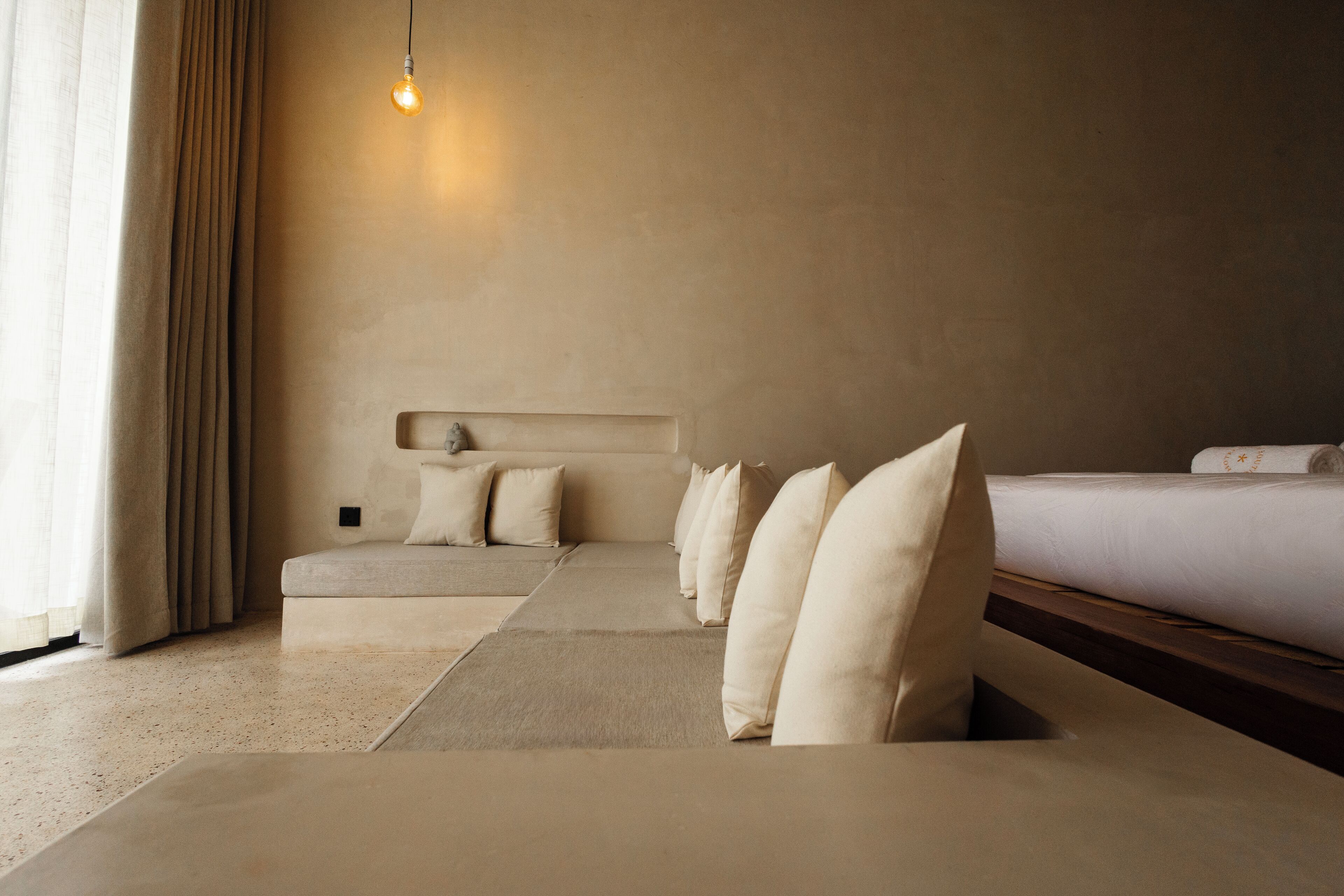 A modern bedroom with a large bed, a sofa, and a bedside table.