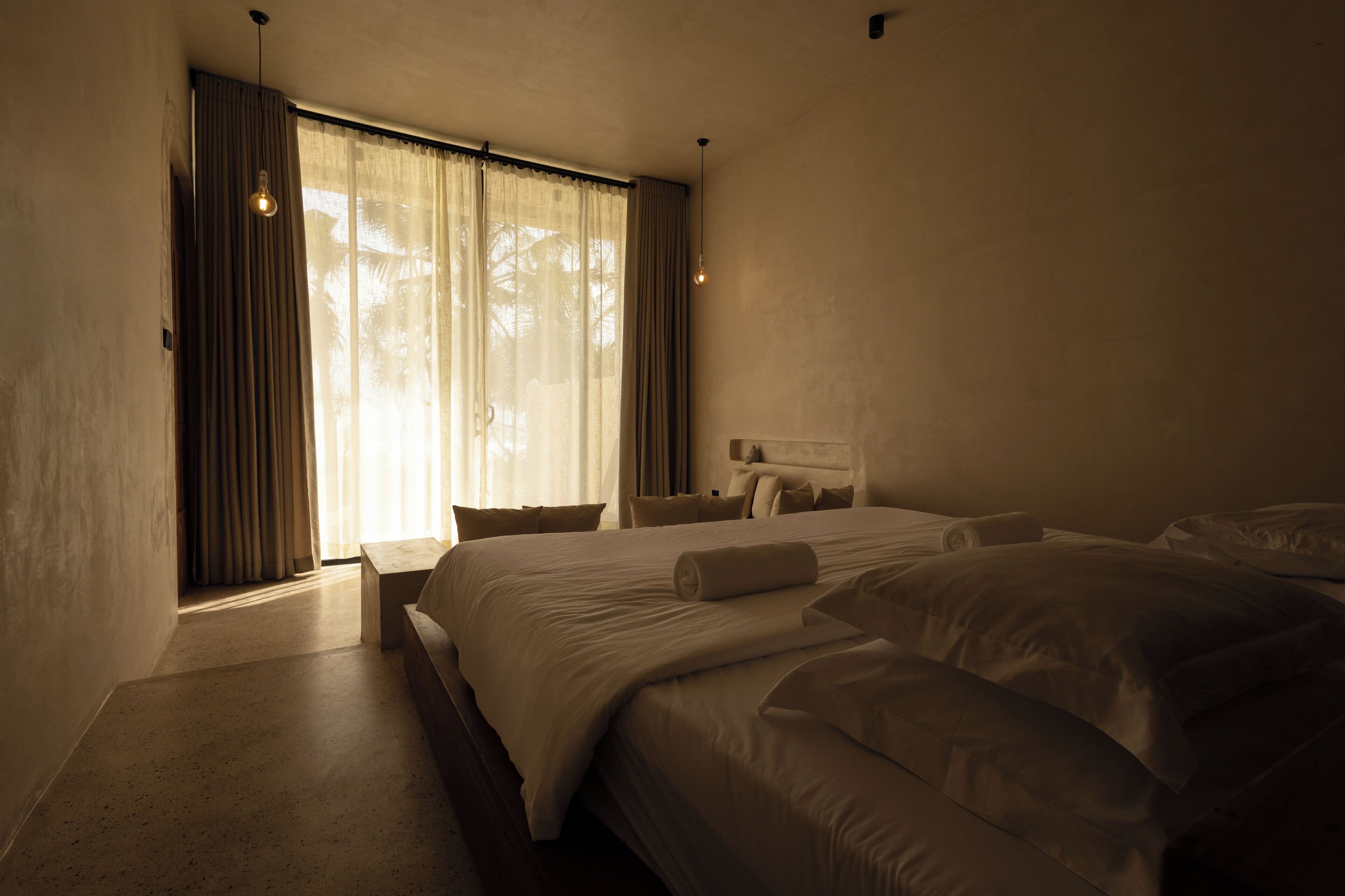 A hotel room with a large bed, a nightstand, and a window with curtains.