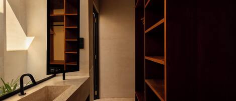 A modern bathroom with a large sink, a mirror, and wooden shelving.
