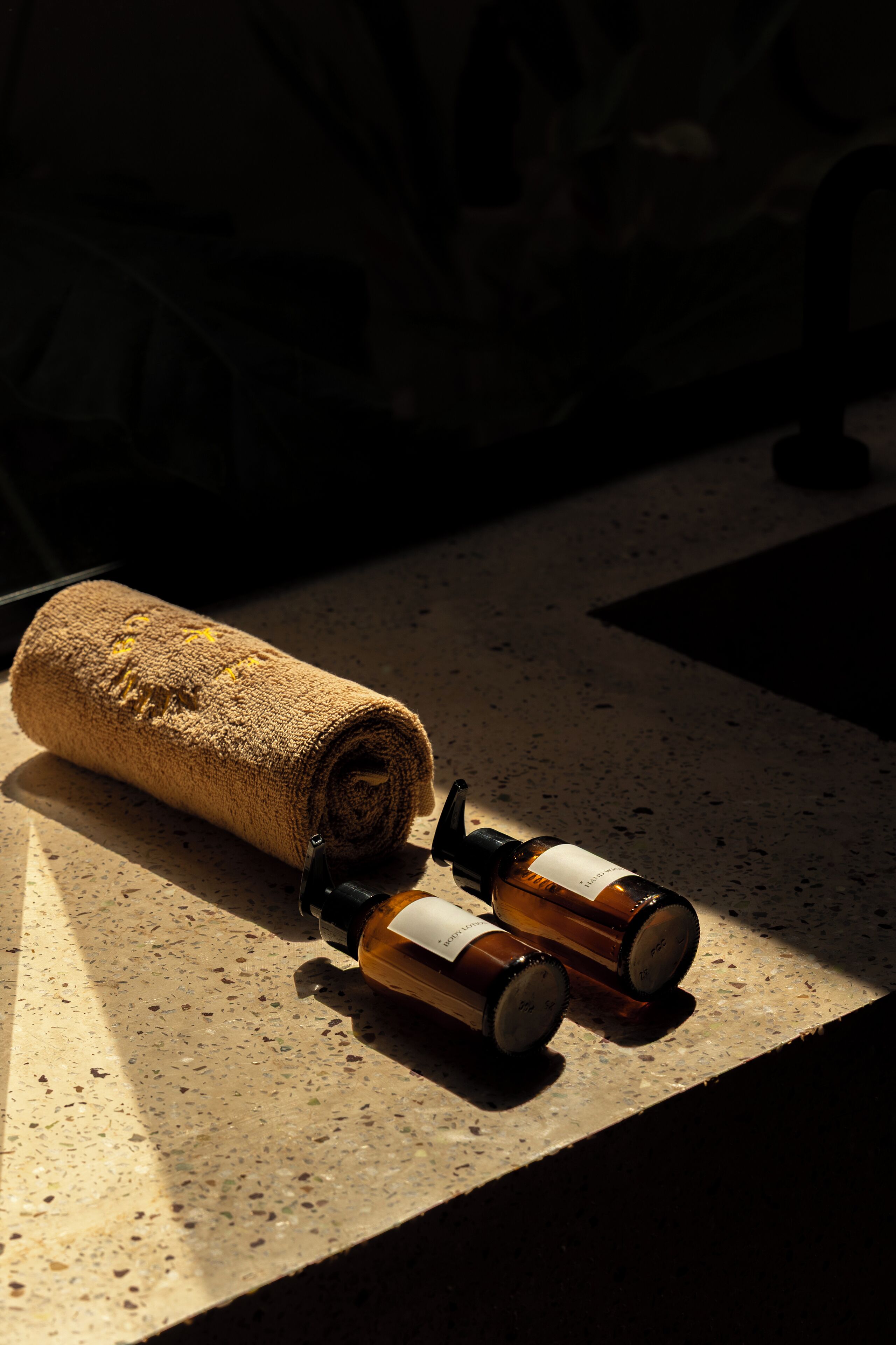 A towel and two bottles on a speckled countertop.