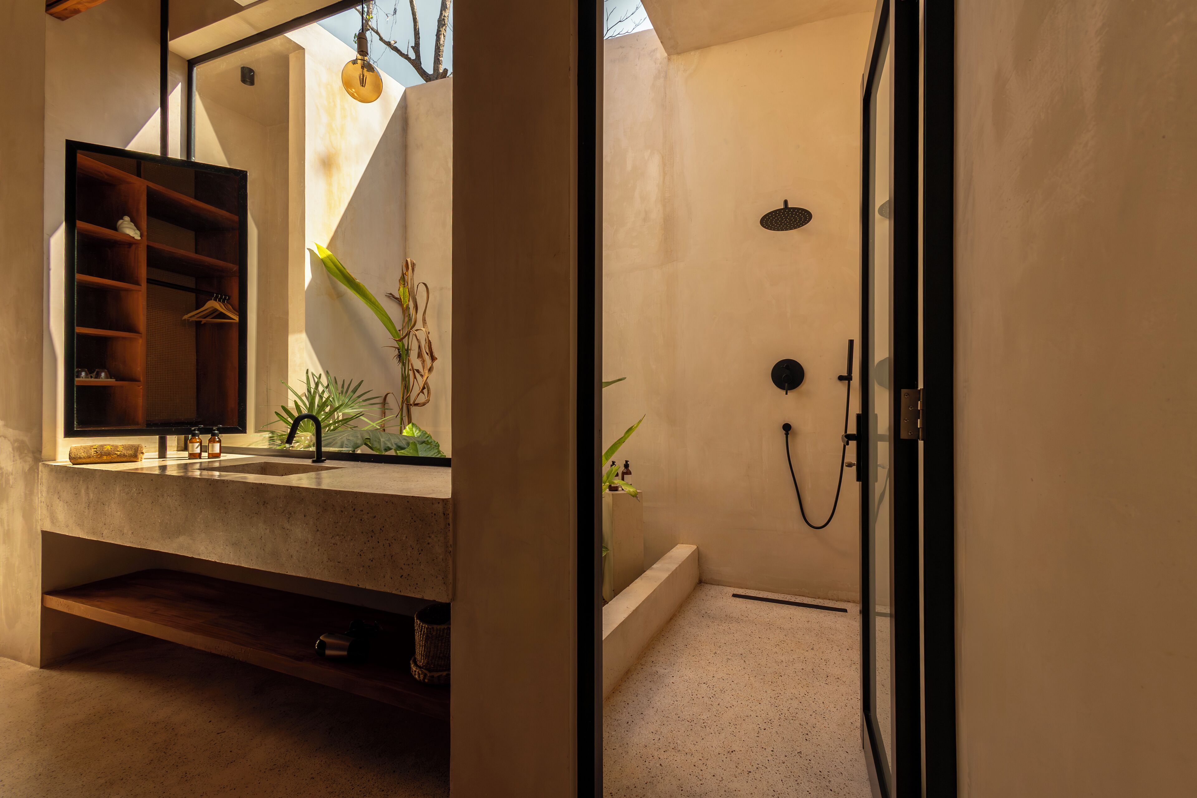 Une salle de bain moderne dotée d’une douche intégrée, d’un meuble-lavabo avec miroir et d’une étagère où sont suspendus divers objets.