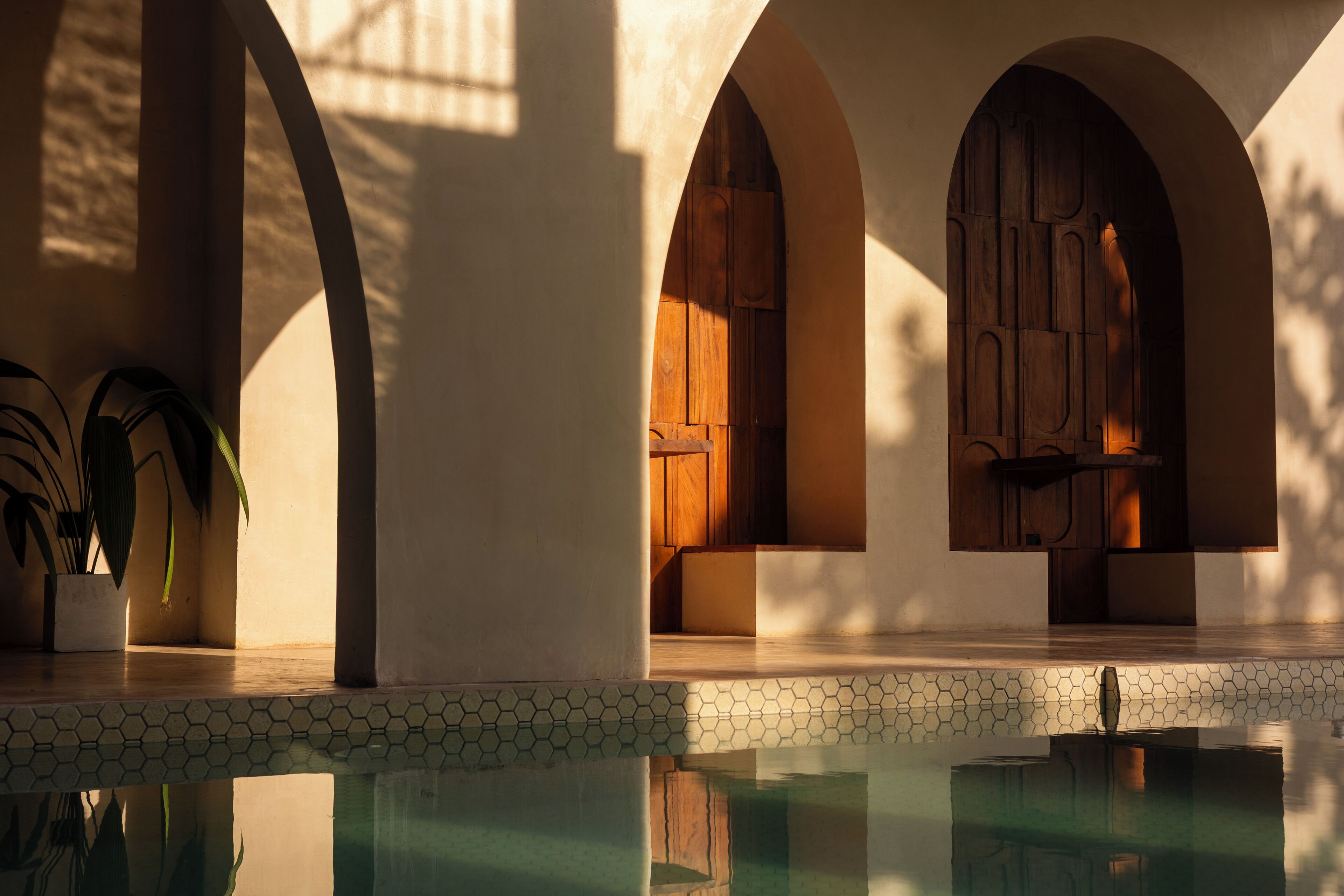A pool area with tiled flooring and arched doorways.