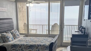 A bedroom with a bed, a desk, and a view of the sea. - Beachfront Suite in Daytona Beach, FL with direct full ocean view!  5th Floor (Daytona Beach)