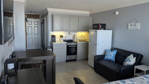 A compact kitchen with a dining table, a black couch with decorative pillows, and a microwave on the counter. - Beachfront Suite in Daytona Beach, FL with direct full ocean view!  5th Floor (Daytona Beach)