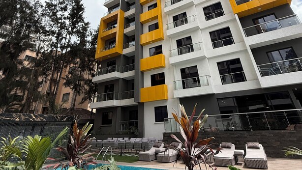 A high-rise building with multiple balconies, a swimming pool, and outdoor seating.