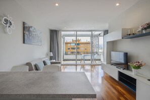 A modern living room with a sofa, a coffee table, a TV, and a balcony with a city view. - Modern Penthouse with Terrace and Parking (Firenze)