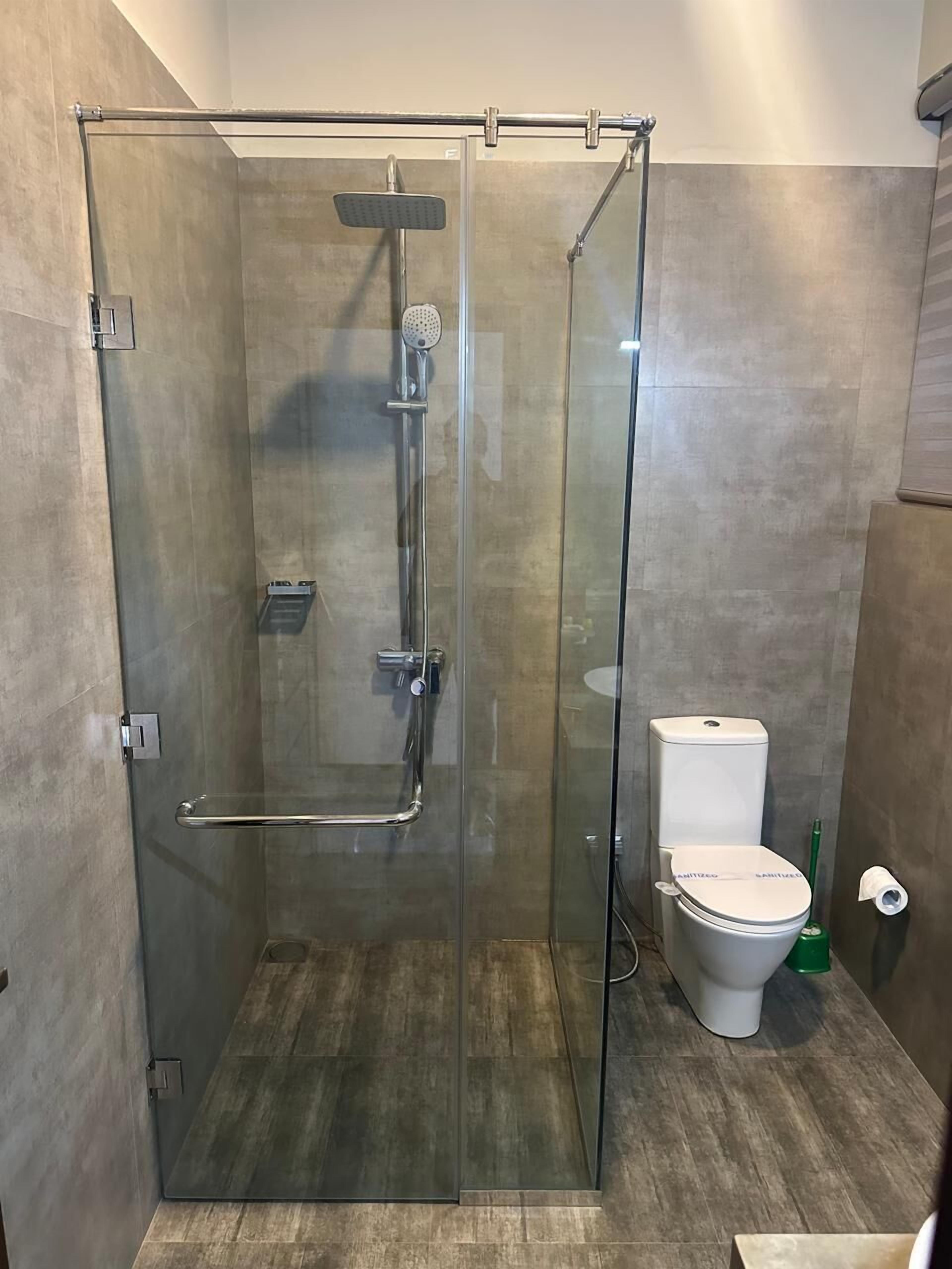 A modern bathroom with a glass-enclosed shower, a toilet, and a bidet.