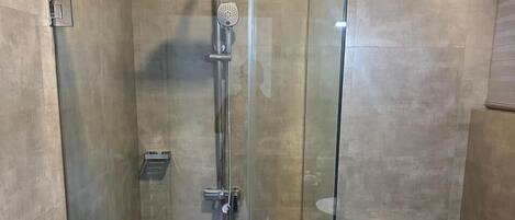 A modern bathroom with a glass-enclosed shower, a toilet, and a bidet.