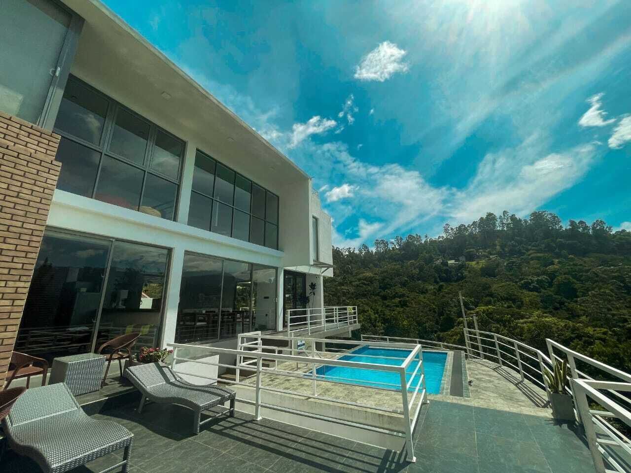 A modern building with a rooftop pool, outdoor seating, and a scenic view of the surrounding forest.