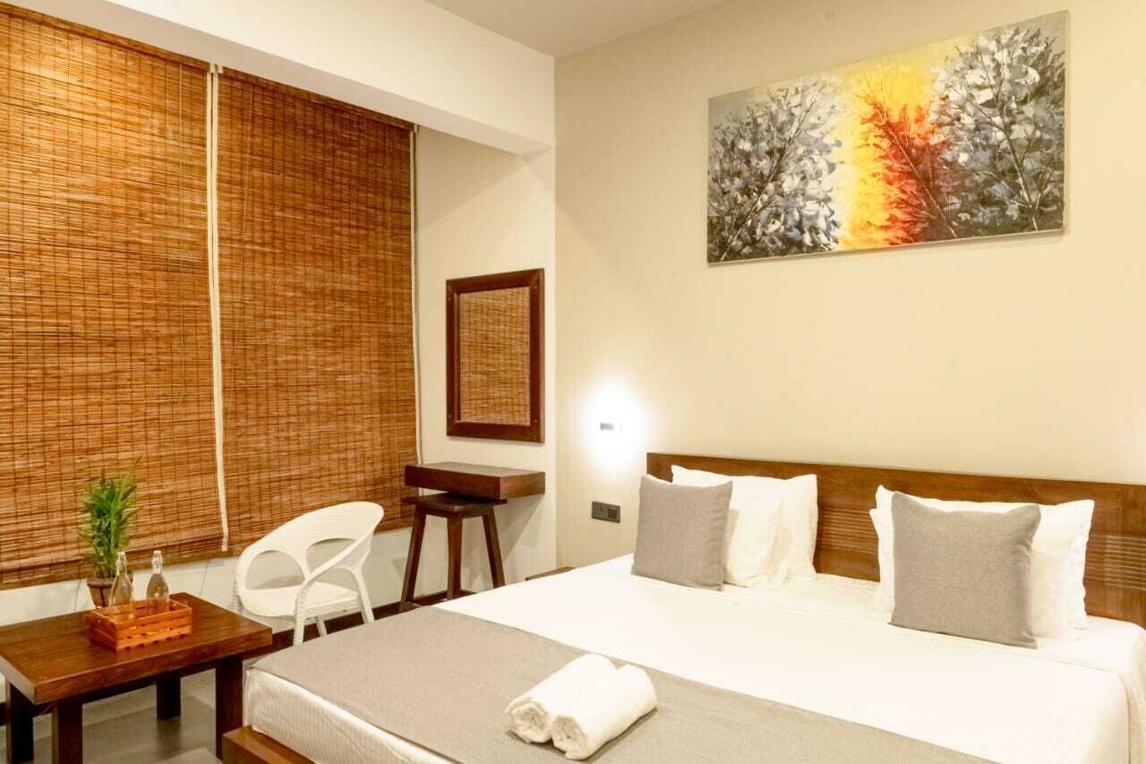 A hotel room with a bed, a desk, a chair, and a painting on the wall.