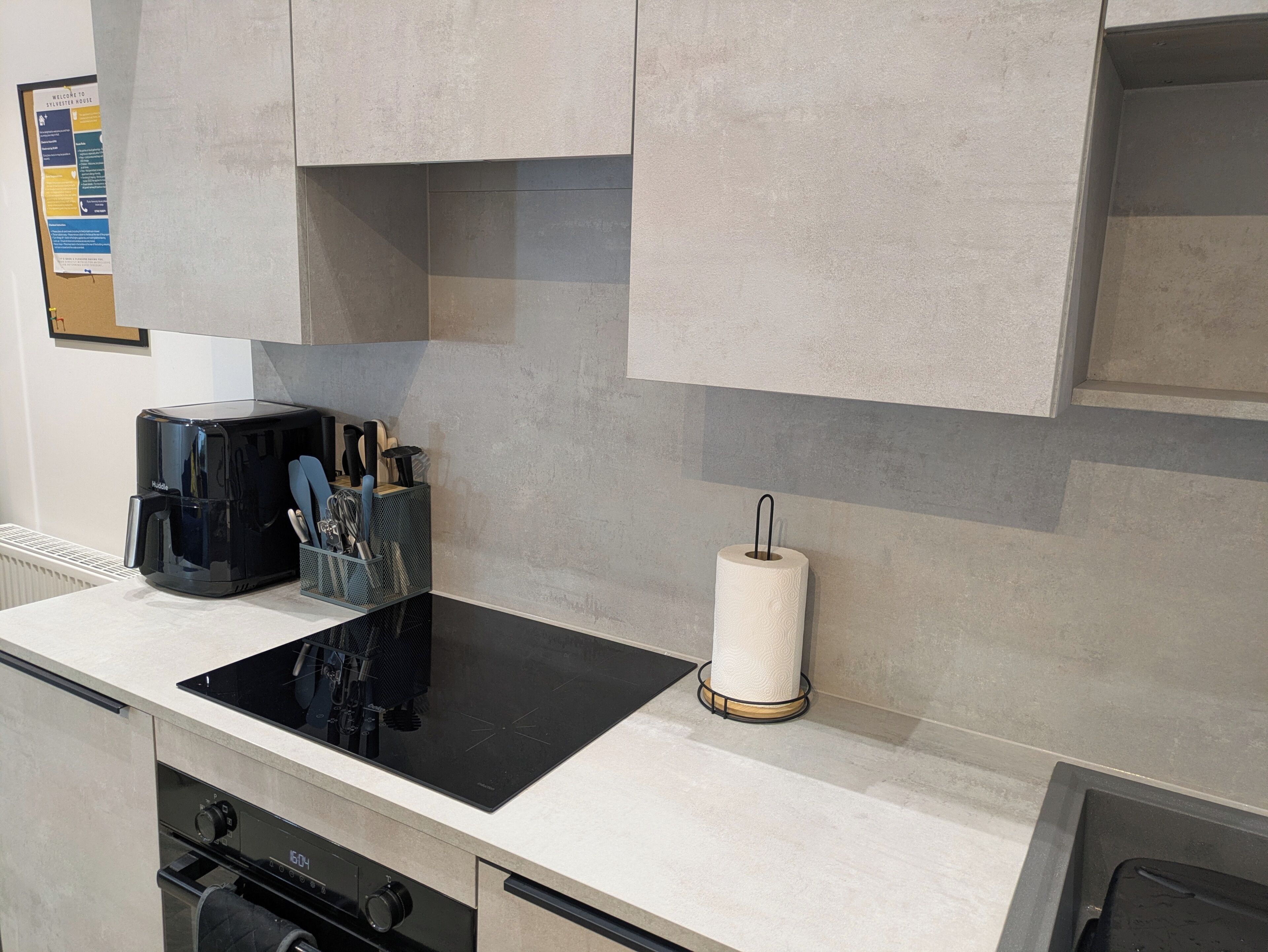 A kitchen with a black induction cooktop, a coffee maker, and a paper towel holder.