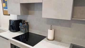 A kitchen with a black induction cooktop, a coffee maker, and a paper towel holder.