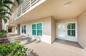 A building with a covered walkway, multiple windows with shutters, and a door.