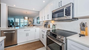 A modern kitchen with white cabinetry, stainless steel appliances, and a built-in oven.