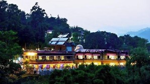 Un hôtel composé de plusieurs bâtiments, doté de panneaux solaires et entouré d’une végétation luxuriante.