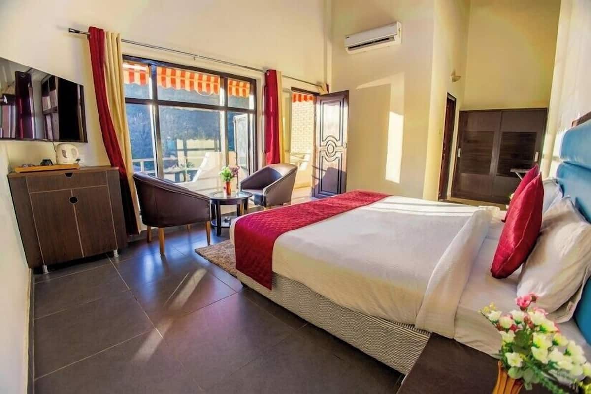 Hotellihuone, jossa on sänky, työpöytä, tuoli, vaatekaappi ja ikkuna, jossa on verhot.