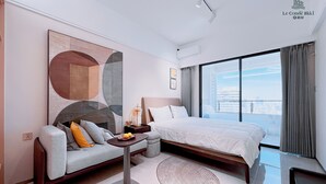 Ein modernes Hotelzimmer mit einem großen Bett, einer Sitzecke, einem kleinen Tisch und Blick auf die Stadt.